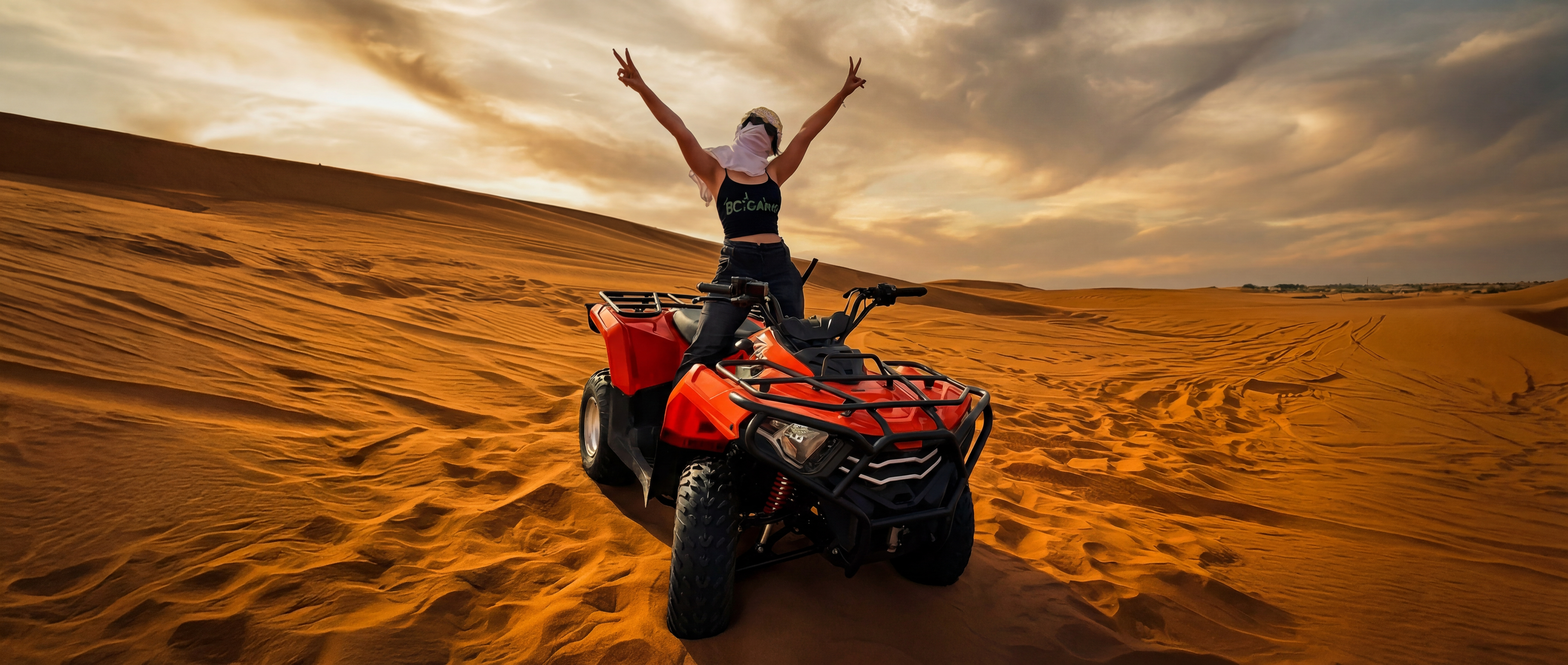 Jana on a quad bike in the Dubai desert — arms up, pure freedom energy